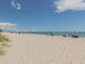 Beach scene with people relaxing on the sand and swimming in the clear blue water at 2020 E Crest Dr, Englewood, FL 34223