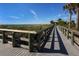 Wooden boardwalk leading to the beach, surrounded by lush greenery and palm trees at 2020 E Crest Dr, Englewood, FL 34223