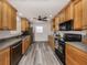Well-lit kitchen featuring wood cabinets, stainless steel appliances, and modern gray vinyl flooring at 2020 E Crest Dr, Englewood, FL 34223