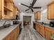 Well-lit kitchen featuring wood cabinets, stainless steel appliances, and modern gray vinyl flooring at 2020 E Crest Dr, Englewood, FL 34223