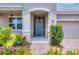 Inviting entryway featuring a light blue front door, decorative plants, and brick paver walkway at 2034 Mesic Hammock Way, Venice, FL 34292