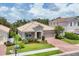 Charming single-story home featuring a clay tile roof, brick paver driveway, and well-manicured landscaping at 2034 Mesic Hammock Way, Venice, FL 34292