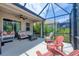 This covered patio features ample seating, including cozy sofa, chairs, and a ceiling fan for comfortable outdoor living at 2034 Mesic Hammock Way, Venice, FL 34292