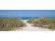 Inviting beach entrance through sea grass to a tranquil ocean view with turquoise water at 205 Louella Ln, Nokomis, FL 34275