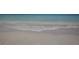 Calm wave gently washing ashore on a pristine, sandy beach with crystal-clear water at 205 Louella Ln, Nokomis, FL 34275
