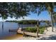 Scenic waterfront view featuring a wooden dock, sandy beach area, and lush greenery at 205 Louella Ln, Nokomis, FL 34275