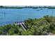 Beautiful waterfront view with private dock on blue water, surrounded by lush tropical trees at 205 Louella Ln, Nokomis, FL 34275