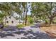 Exterior home view with a long driveway, mature trees offering shade, and ample parking, set in a tranquil environment at 205 Louella Ln, Nokomis, FL 34275