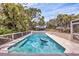 Beautiful backyard pool with clear water, surrounded by lush greenery and a covered car port in the background at 205 Louella Ln, Nokomis, FL 34275