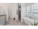 Bathroom featuring a freestanding tub, glass shower, and gray cabinets at 209 E Venice Ave, Venice, FL 34285