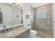 Bathroom with a tiled shower, gray vanity, granite counters, and decorative mirror at 209 E Venice Ave, Venice, FL 34285