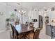 Dining area with a chandelier, neutral walls, wood table set for six, and natural light streaming through the window at 209 E Venice Ave, Venice, FL 34285