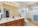 Modern bathroom with double sinks, framed mirror, glass shower, and natural lighting at 2104 Batello Dr, Venice, FL 34292