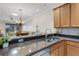 Open kitchen with granite countertops, stainless steel sink, wooden cabinets, and views to the living area at 2104 Batello Dr, Venice, FL 34292