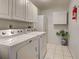 Efficient laundry room with washer, dryer, storage cabinets, and neutral tiling at 2194 Abalom St, Punta Gorda, FL 33980