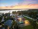 Waterfront estate featuring a screened pool, rooftop deck, mature landscaping, and sunset views at 2322 Bayshore Rd, Nokomis, FL 34275