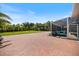 Spacious backyard patio featuring brick pavers, a screened-in porch, and tropical landscaping at 2322 Bayshore Rd, Nokomis, FL 34275
