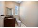 Bathroom vanity with dark cabinets, granite counters, toilet, framed mirror, and window at 2322 Bayshore Rd, Nokomis, FL 34275