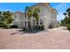 Expansive brick paver driveway leading to a beautiful home with mature landscaping, stone mulch, and palm trees at 2322 Bayshore Rd, Nokomis, FL 34275