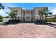 Gorgeous two-story home showcasing a balcony, white columns, a brick driveway, and well-manicured landscaping at 2322 Bayshore Rd, Nokomis, FL 34275