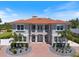 Stunning two-story home featuring a Spanish tile roof, balcony, and a brick paver driveway with circular garden beds at 2322 Bayshore Rd, Nokomis, FL 34275