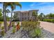 Beautifully landscaped front yard with colorful flowers, mature palm trees, and a circular paver driveway at 2322 Bayshore Rd, Nokomis, FL 34275