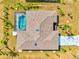 Aerial view of a house with a screened in pool and a gray driveway with landscaping at 269 Mark Twain Ln, Rotonda West, FL 33947