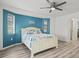 Bright bedroom featuring blue accent wall, ceiling fan, and wood-look floors at 269 Mark Twain Ln, Rotonda West, FL 33947