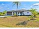 A single-story home boasts a well-manicured lawn, mature palms, and a charming exterior design at 269 Mark Twain Ln, Rotonda West, FL 33947