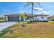 Beautiful single-story home with a well-manicured lawn, mature palm trees, and attached garage at 269 Mark Twain Ln, Rotonda West, FL 33947