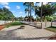 Spacious backyard featuring a stone patio, a fire pit, and a distant view of a shed with large trees at 2769 Dode Ave, North Port, FL 34288