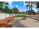 Spacious backyard with a stone patio, fire pit, green lawn, and white picket fence at 2769 Dode Ave, North Port, FL 34288