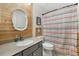 Cozy bathroom featuring wood accent wall, stylish mirror, and attractive colorful shower curtain at 2769 Dode Ave, North Port, FL 34288