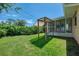 Backyard view showing a covered outdoor structure, an enclosed lanai, and lush landscaping at 331 Bucknell Rd, Venice, FL 34293
