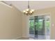 Bright dining area with a chandelier and sliding doors leading to a sunroom with views of lush greenery at 331 Bucknell Rd, Venice, FL 34293