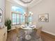Dining area with a white table, four chairs, modern chandelier, large window, and hardwood floors at 333 Sunrise Dr, Nokomis, FL 34275
