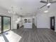 Open-concept living room and kitchen with gray floors, white cabinets, and stainless steel appliances at 3588 Erie Ct, North Port, FL 34287