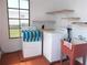 Bright laundry room featuring a washing machine, dryer, utility sink, and ample shelving for storage needs at 373 Longwood Dr, Venice, FL 34285