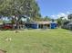Large backyard with grass, deck and patio with table, chairs and mature shade tree in view at 413 Valencia Rd, Venice, FL 34285