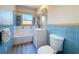 Bathroom featuring blue tile and yellow accents, a white vanity and toilet and a white bath tub at 413 Valencia Rd, Venice, FL 34285