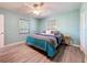 Bedroom with a ceiling fan, wood floors and a queen bed with a colorful comforter and two windows at 413 Valencia Rd, Venice, FL 34285