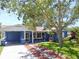 Charming blue single-story home with a well-manicured lawn and mature trees at 413 Valencia Rd, Venice, FL 34285