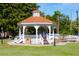 Picturesque white gazebo with a tile roof, set on a manicured lawn with benches and landscaping at 413 Valencia Rd, Venice, FL 34285