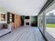 Living room with a gray couch, wood floors, fireplace, TV and glass doors leading to a backyard at 413 Valencia Rd, Venice, FL 34285