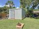 Backyard shed with double doors, surrounded by green grass and lush landscaping at 413 Valencia Rd, Venice, FL 34285