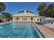 Community pool area showcases ample lounge chairs, inviting pool water, and a clubhouse for residents' enjoyment at 418 Cerromar Ct # 158, Venice, FL 34293