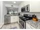 Modern kitchen featuring stainless steel appliances, granite countertops, and white cabinetry at 418 Cerromar Ct # 158, Venice, FL 34293