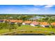 Community aerial view with lush landscaping, pond, and homes with orange tile roofs under a bright blue sky at 4378 Summertree Rd, Venice, FL 34293
