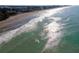 Aerial view of the beach with surfers in the clear turquoise water on a sunny day at 491 Cervina Dr, Venice, FL 34285