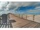 Wooden boardwalk with ocean view and railings under a cloudy sky at 491 Cervina Dr, Venice, FL 34285